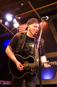 Bild zeigt den Mülheimer Musiker Klaus Vanscheidt auf der Bühne mit einer Gitarre. Er trägt ein schwarzes Cap.